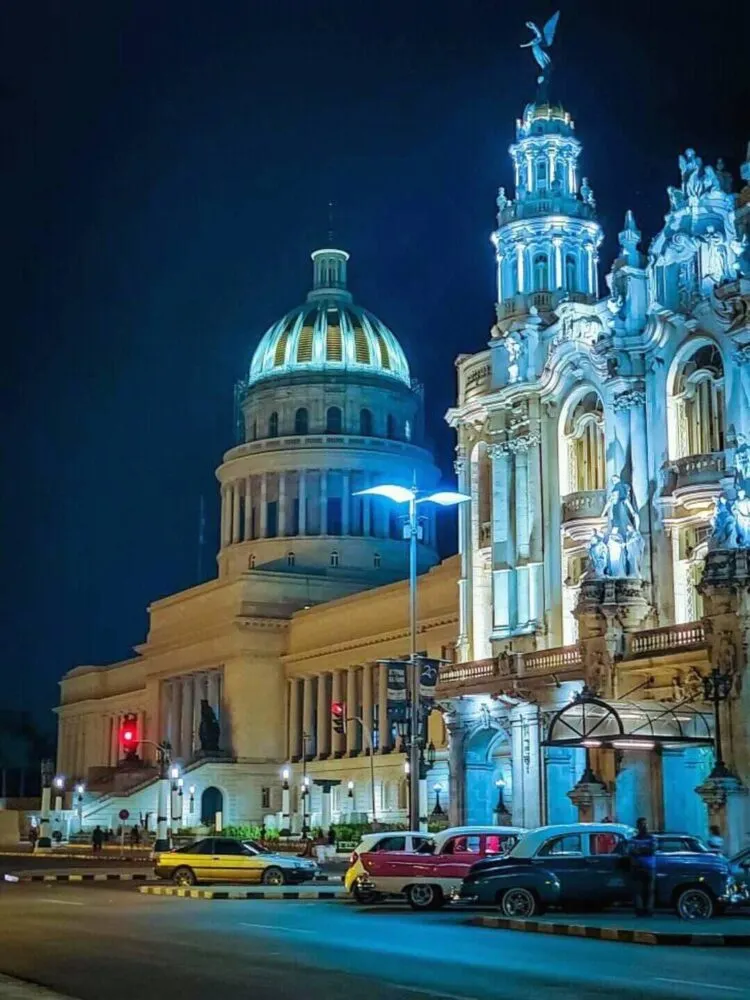 El Capitolio building at night and cars parked in front of it