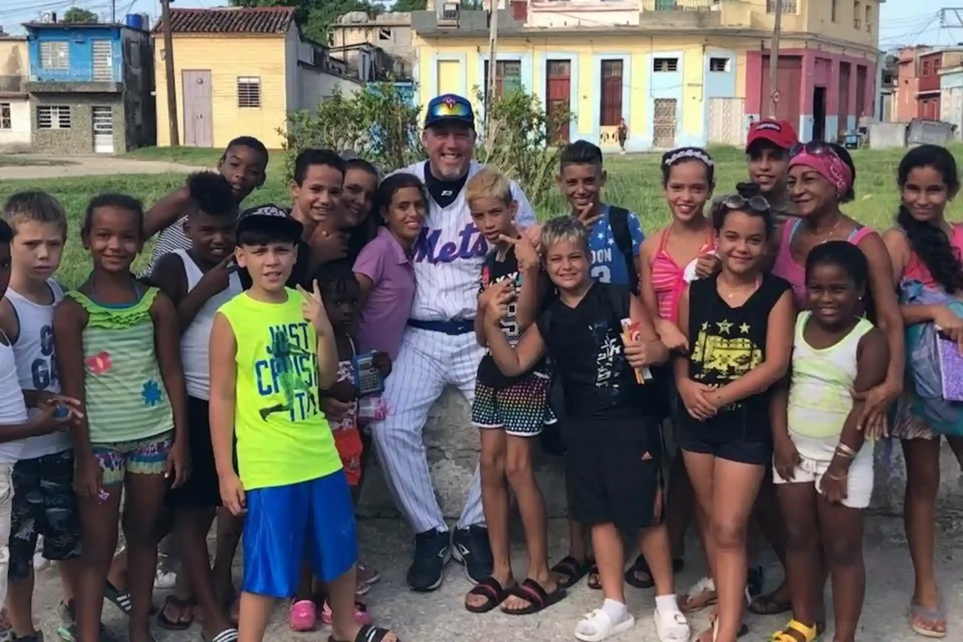 A group of about 25 young kids with a professional baseball player from the Mets team